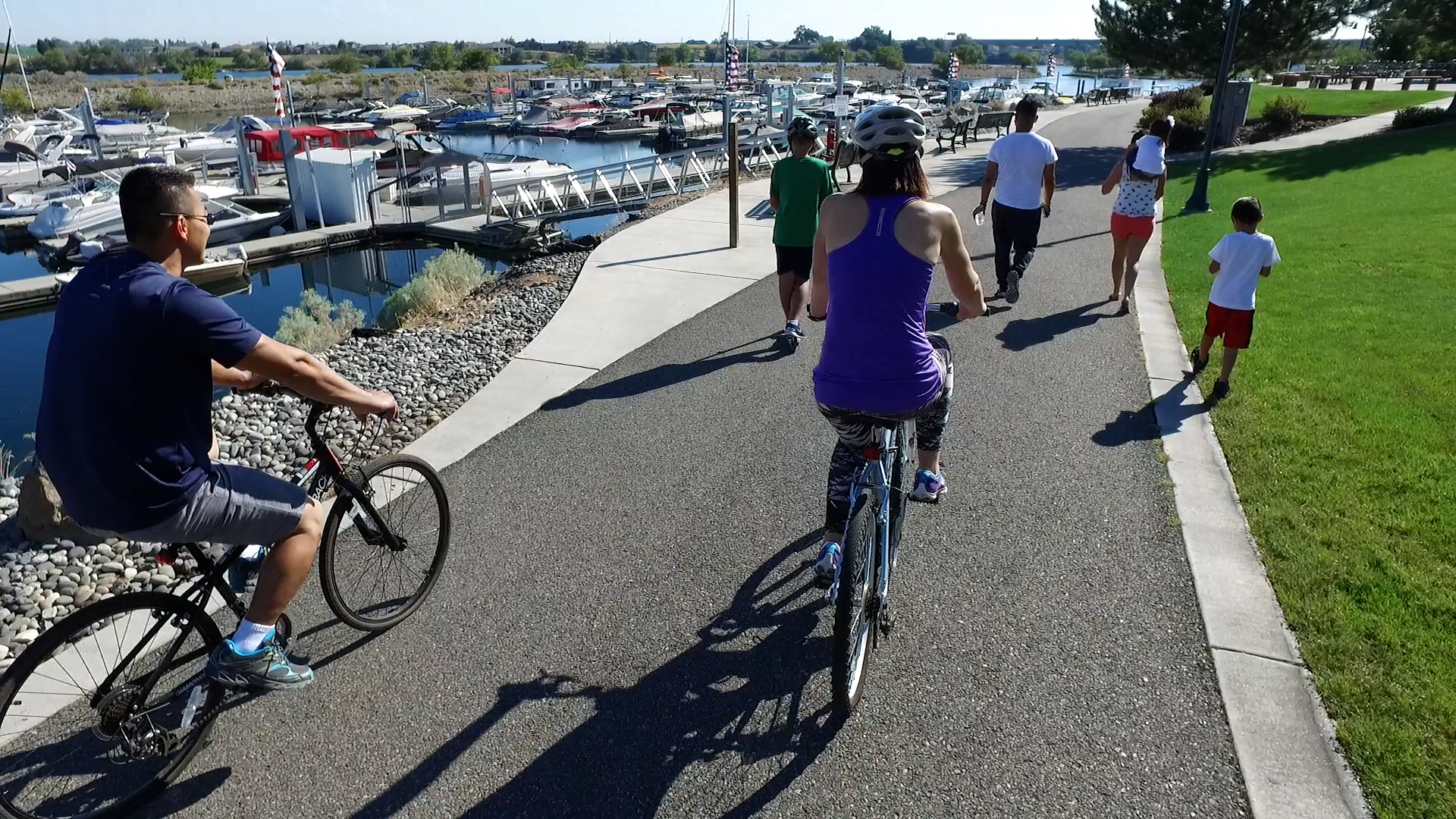 group bicycle riding along riverfront trail by marina