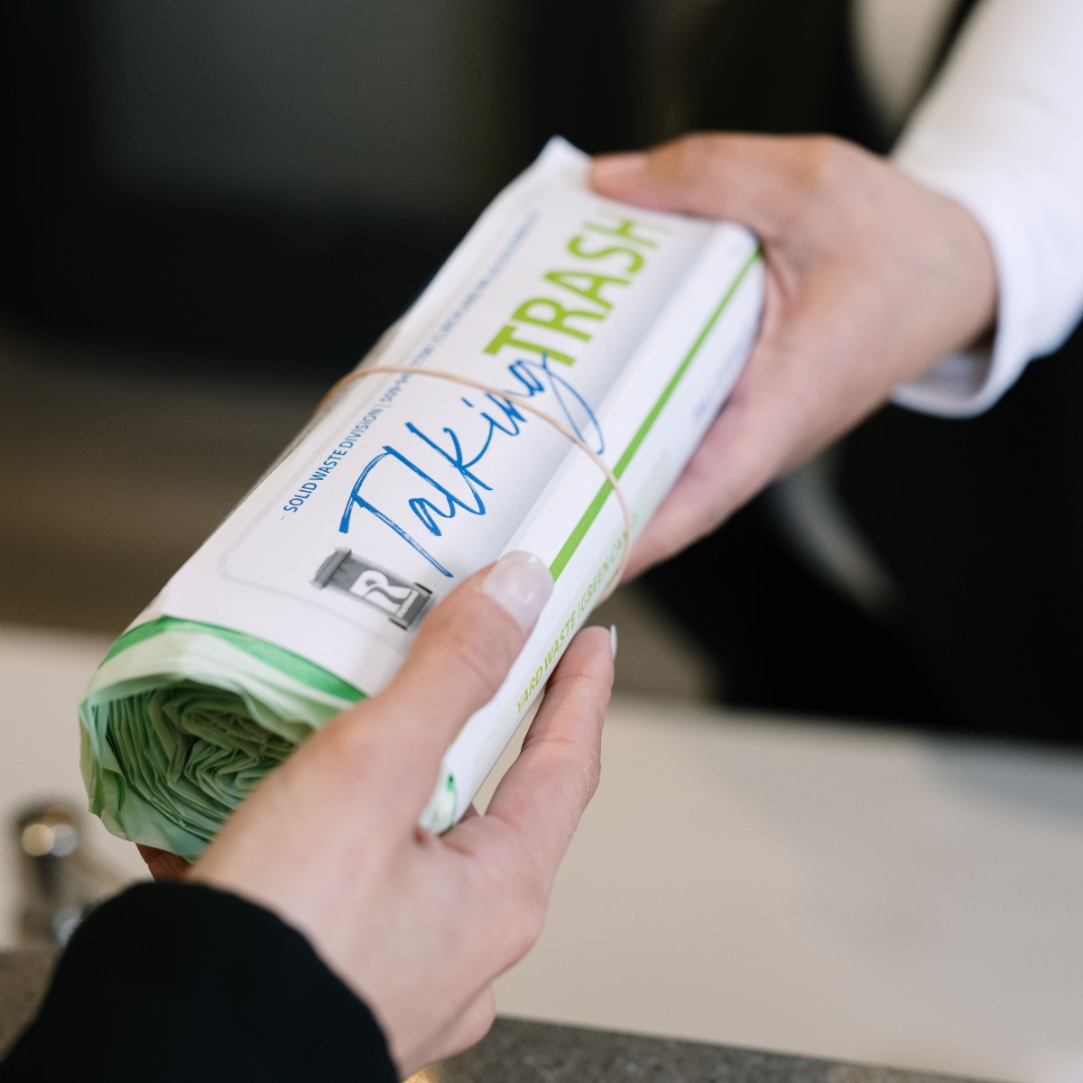 Hands Handing off a roll of bags