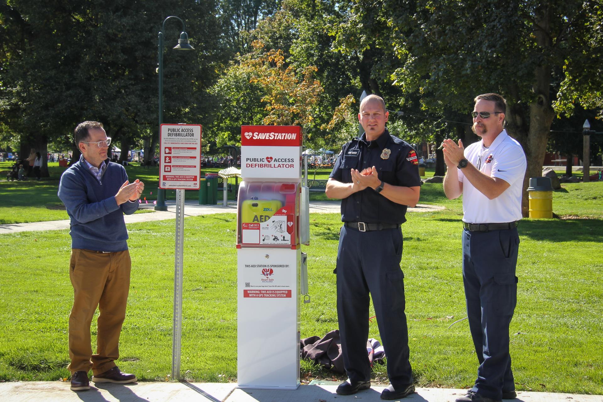 City Manager Jon Amundson, Battalion Chief Mike Van Beek, and Fire Chief Tom Huntington unveil the new AED located in Howard Amon Park